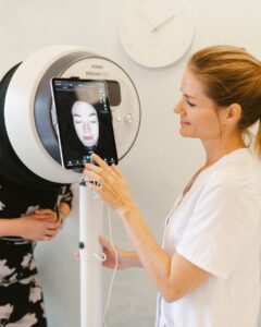 Huidtherapeut Saskia in een behandelkamer die een foto maakt van een cliënt met de Observ Huidanalyse